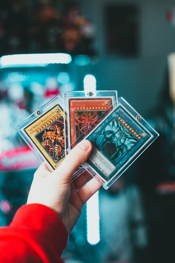 Close-up of a hand holding collectible trading cards in protective cases.